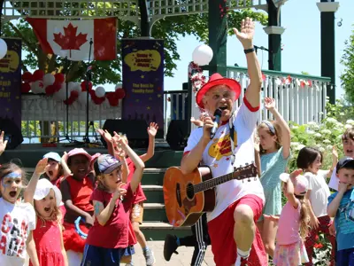 Dan the Music man and children singing in park in front of gazebo