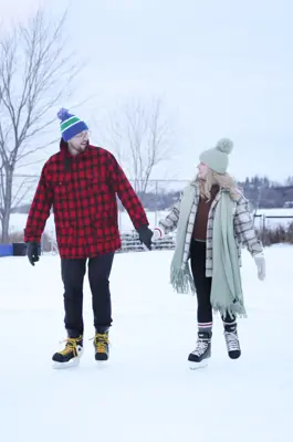 A couple skating on outdoor rink holding hands
