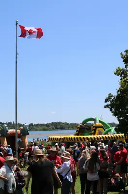 crowd around Canada flag and inflatable play equipment on Canada Day